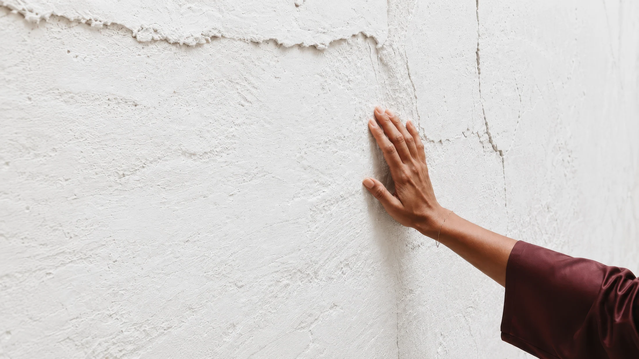 A hand touches a pale mineral surface.
