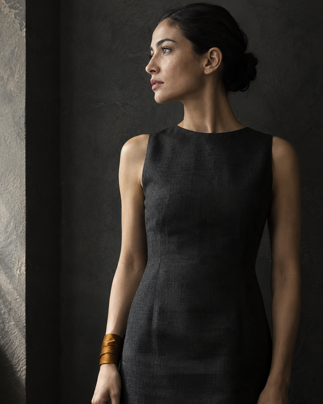 A woman in a charcoal dress wears a single amber-coloured fabric cuff.